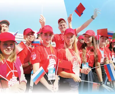 Russian students hold Chinese and Russian national flags to welcome Chinese guests. (Photo by Qu Pei from People’s Daily)