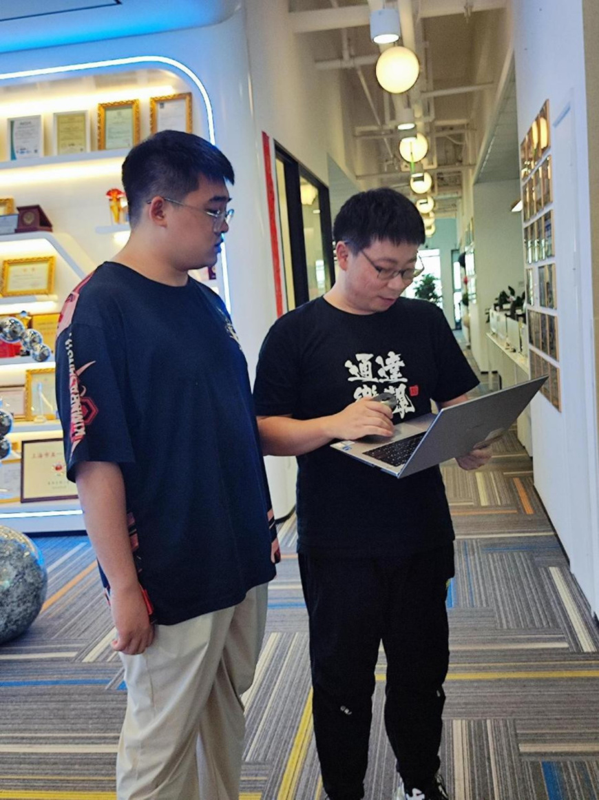 Yang Hongxu (right) discusses AI training progress with a colleague. (Photo by Huang Xiaohui/People's Daily)