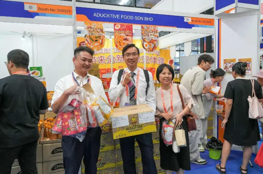 Visitors to the 21st China-ASEAN Expo pose for a picture with the goods they have purchased, Sept. 25, 2024. (Photo by Zhu Xiaoming/People's Daily Online)