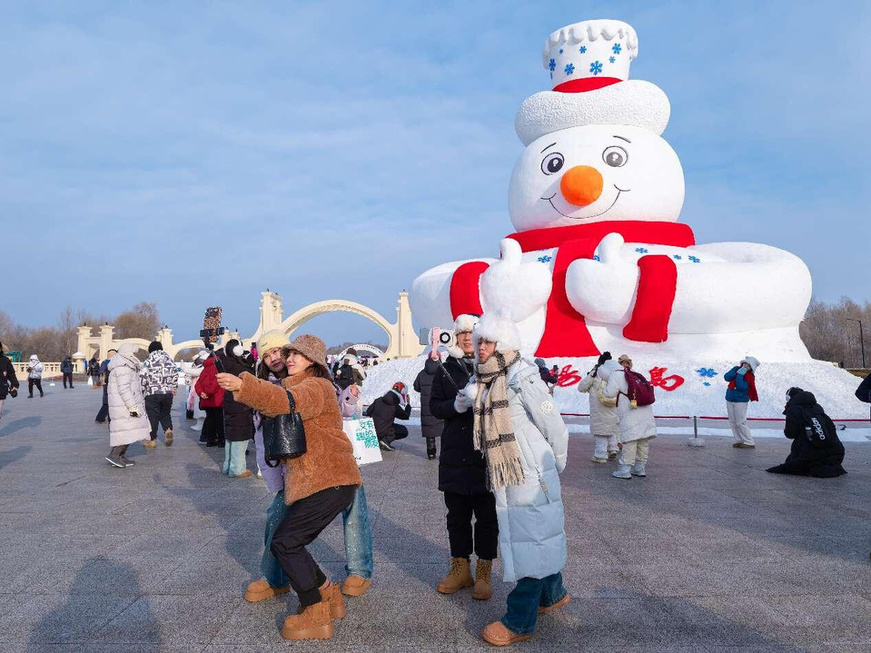 Tourists pose for pictures in front of a gigantic snowman at the 37th Sun Island International Snow Sculpture Art Expo in Harbin, northeast China's Heilongjiang province, Dec. 23, 2024. (Photo by Geng Hongjie/People's Daily Online)