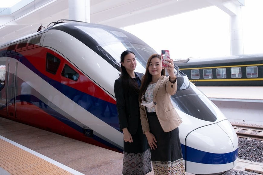 Two women pose for photos with the Lane Xang EMU train at the China-Laos railway Vientiane station in the Lao capital Vientiane, Oct. 16, 2021. (Photo by Kaikeo Saiyasane/Xinhua)