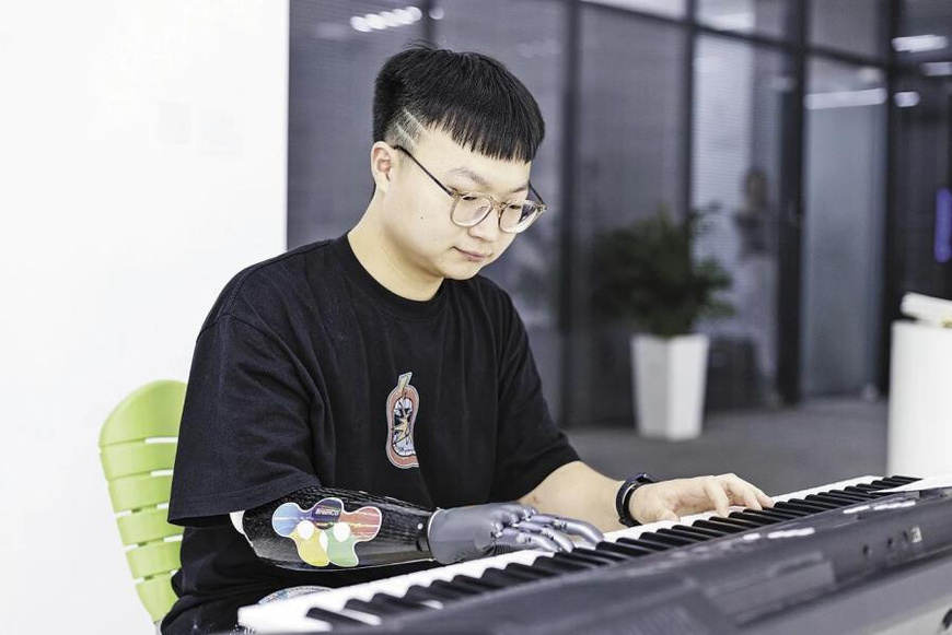 Photo shows Zhou Jian playing piano with his bionic hand.(Photos provided by interviewees.)