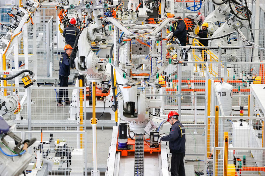 Workers work in collaboration with robotic arms in a workshop of Shanghai Junyi Industrial Automation Co., Ltd. (Photo by Jiang Huihui/People's Daily Online)