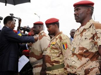 Le président tchadien Idriss Deby Itno (G) décore le général du contingent tchadien au Mali Oumar Bikimo (G) et le commandant en second Mahamat Idriss Déby Itno, son fils (C) lors de la cérémonie de bienvenue. Ndjamena, le 13 mai 2013. AFP PHOTO / STR