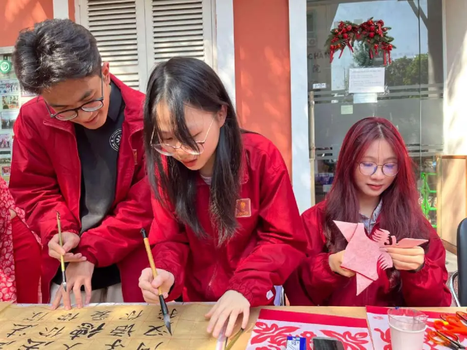 Students try Chinese calligraphy and paper cutting during a cultural activity hosted by the Confucius Institute at Hanoi University, Dec. 8. (Photo by Zhang Yuannan/People's Daily)
