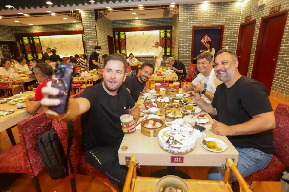 Merchants attending the 135th session of the China Import and Export Fair held in Guangzhou, south China's Guangdong province pose for a picture while tasting Guangdong food in a local restaurant, on April 17, 2024. (Photo by Chen Zhiqiang/People's Daily Online)
