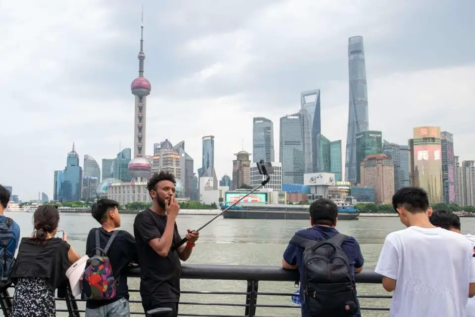 A foreign visitor takes photos at the Bund in east China's Shanghai, July 10. (Photo by Weng Qiyu/People's Daily Online)