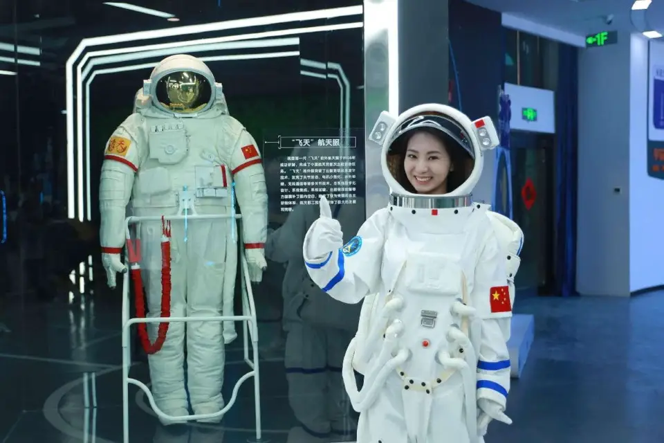 A woman poses for a picture in a spacesuit model in a space science museum in Jiuquan, northwest China's Gansu province. (Photo by Chen Kun/People's Daily Online)