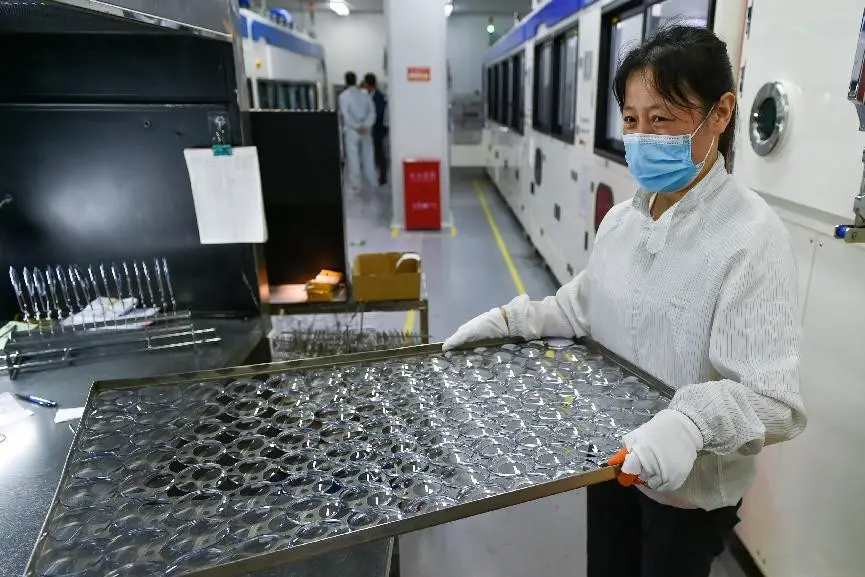 A worker works in an optical lens factory in Danyang, east China's Jiangsu province. (Photo by Fang Dongxu/People's Daily Online)