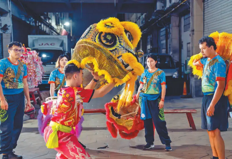 Mai Wangtao (in red) instructs young Peruvians to perform lion dance, including Alfredo (first from left).