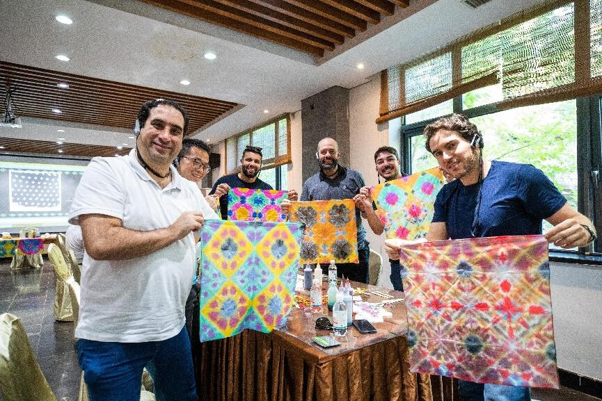 Foreigners pose for a picture with tie-dye works they have made in a folk customs center in Laoshan district, Qingdao, east China's Shandong province, Sept. 28, 2024. (Photo by Yang Xuemei/People's Daily Online)