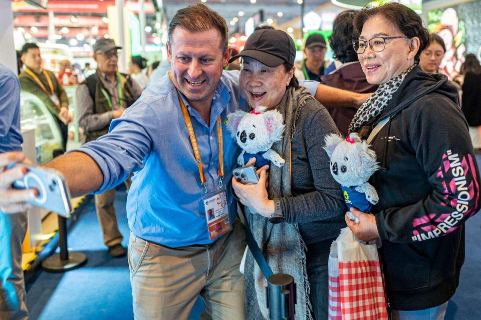 An Australian exhibitor poses for a picture with visitors at the seventh China International Import Expo (CIIE), Nov. 8, 2024. (Photo by Wang Chu/People's Daily Online)